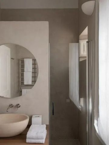 Elegantes Badezimmer im Capofaro Resort mit Rundspiegel und Naturtönen