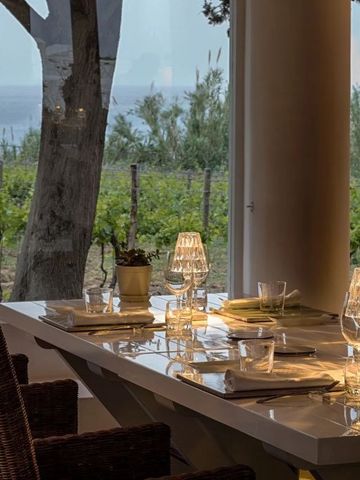 Tisch im Restaurant mit gläsernen Lampen und Blick auf Weinberg und Meer