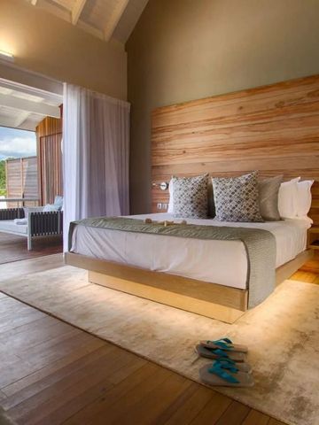 Elegantes Zimmer mit Holzwänden und großem Bett im Hotel Carana Beach