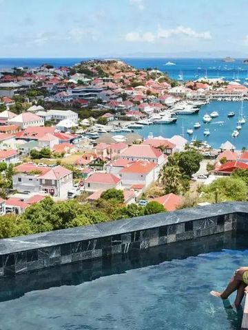 Frau in gelbem Kleid am Infinity Pool mit Blick auf Hafen und Meer in Saint-Barthélemy