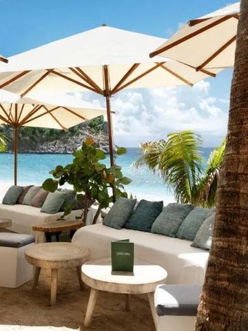Strandlounge mit weißen Sofas und Sonnenschirmen am Meer