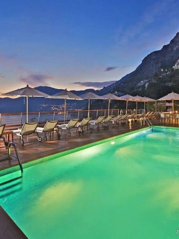 Beleuchteter Pool bei Sonnenuntergang mit Meerblick