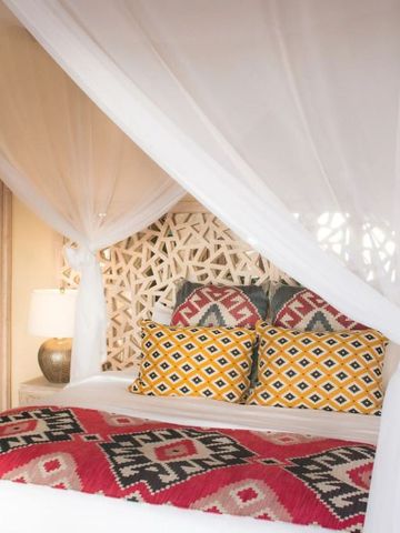 Luxus-Schlafzimmer mit Baldachin-Bett und farbenfrohen Kissen