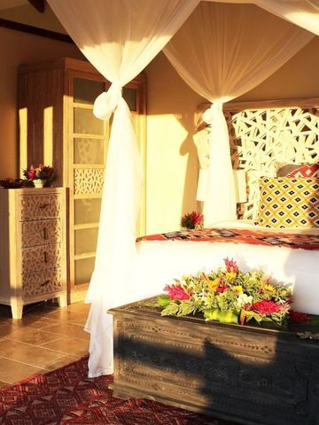 Sonnendurchflutetes Schlafzimmer mit Blumen und Baldachin