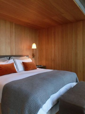 Komfortables Schlafzimmer mit Holzwänden und stimmungsvollem Licht