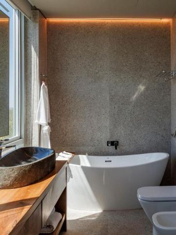 Elegantes Badezimmer mit freistehender Badewanne und Natursteinwaschbecken