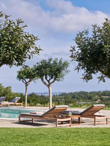 Sonnenliegen und Bäume am Pool mit Blick auf die Landschaft
