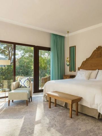 Helles Zimmer mit Kingsize-Bett, großen Fenstern und eleganten Dekorationen.