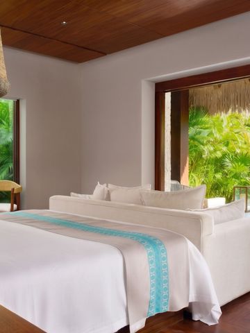 Luxuriöse Suite mit großem Bett und Blick auf tropischen Garten