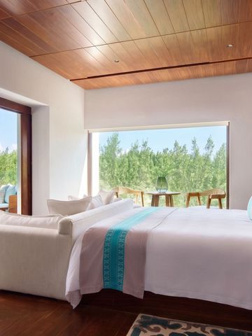 Luxuriöse Suite mit großem Bett und Blick auf den tropischen Garten.