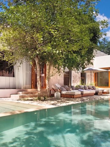 Villa mit Terrasse und Pool umgeben von üppigen Bäumen und Pflanzen