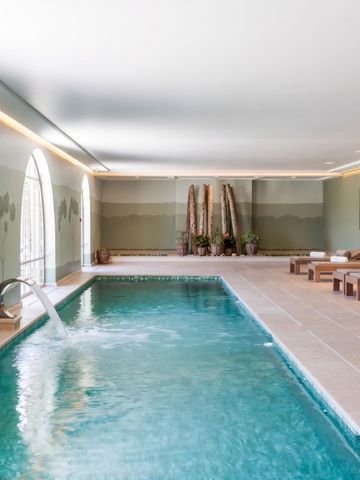 Eleganter Indoor-Pool mit Liegen und Wandkunst im Château de Berne Spa