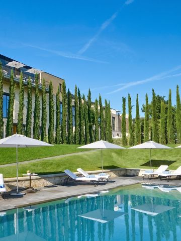 Grüne Gartenlandschaft mit Pool und Sonnenschirmen vor eleganter Architektur