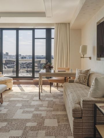 Helles Hotelzimmer mit komfortabler Sitzecke und Balkonzugang.