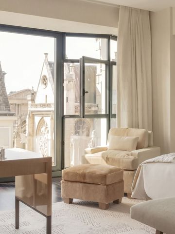 Geräumiges Zimmer mit großer Fensterfront und Ausblick auf historische Architektur.