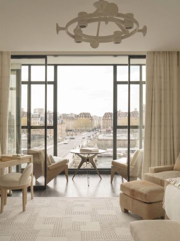 Helles Wohnzimmer mit großem Fenster und Blick über die Dächer von Paris.