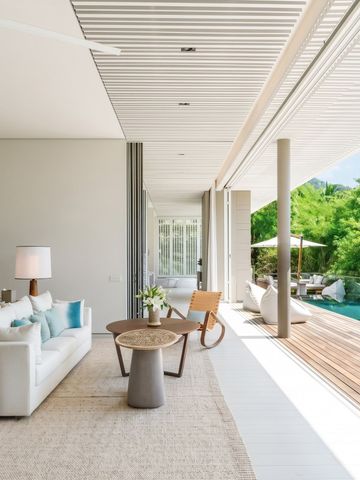 Moderne Lounge mit Zugang zur Terrasse und Blick auf tropische Vegetation.