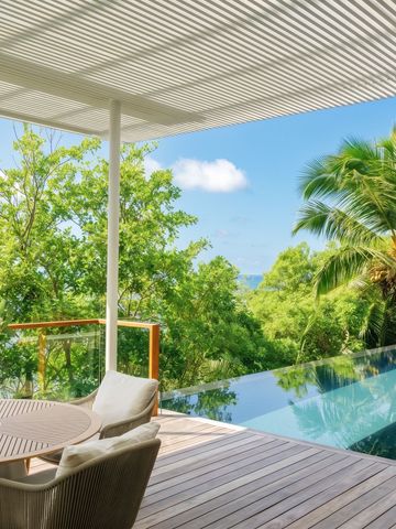 Infinity Pool mit Terrasse, umgeben von tropischen Pflanzen und Palmen.
