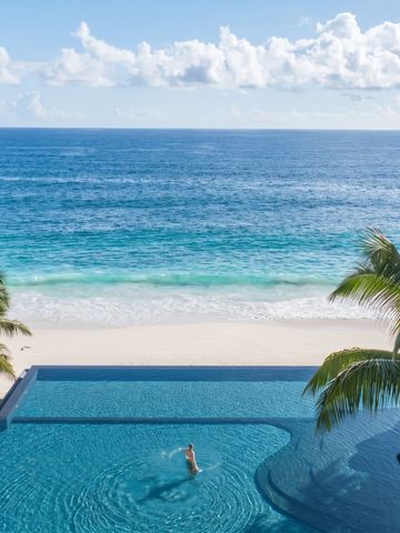 Infinity Pool mit Blick auf den Ozean und weißem Sandstrand im Hintergrund