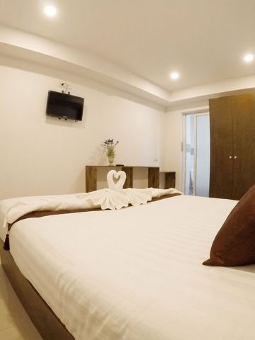 Helles Hotelzimmer mit Flachbildfernseher und dekorativen Kissen