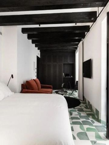 Zimmer mit elegantem Bett, dunklen Holzbalken und modernem Flair
