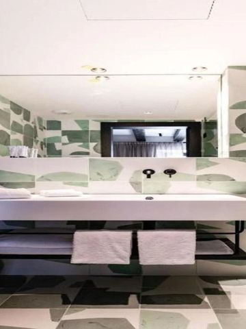Modernes Badezimmer mit großem Spiegel und markanten grünen Fliesen