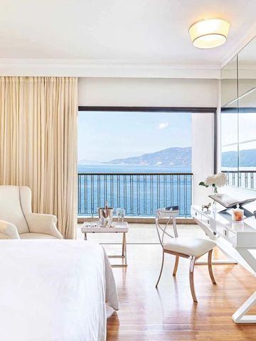 Geräumiges Zimmer mit hellen Farben und Meerblick durch große Fenster.