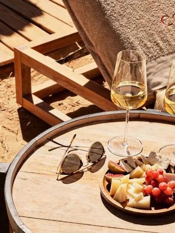 Holztisch am Strand mit Käseplatte und zwei Gläsern Weißwein