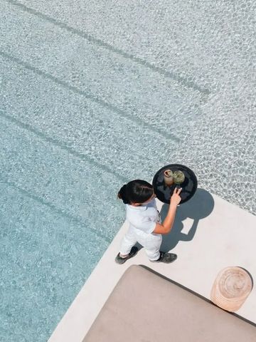 Poolansicht von oben mit Person die Getränke serviert am Cove Paros Hotel