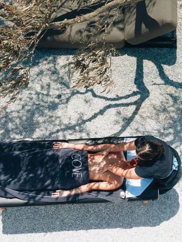 Person genießt Massage unter Baum im Freien im Hotel Cove Paros
