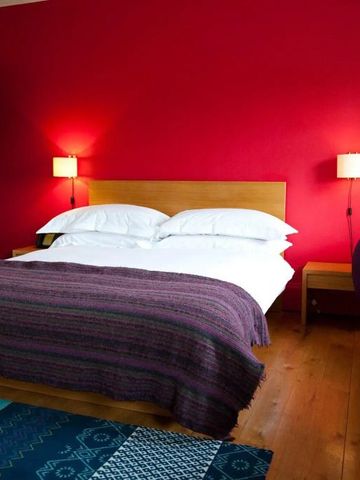 Gemütliches Schlafzimmer mit roter Wand und Doppelbett