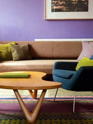 Gemütliches Wohnzimmer mit violetter Wand und modernen Möbeln