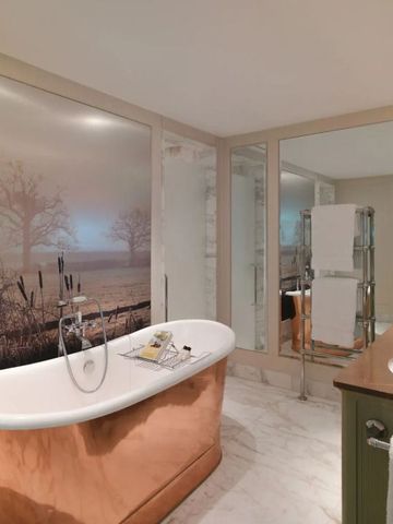 Elegantes Badezimmer mit freistehender Kupferbadewanne und Wandkunst