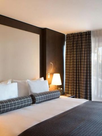 Gemütliches Hotelzimmer mit großen Fenstern und stilvoller Bettwäsche