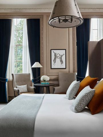 Elegantes Hotelzimmer mit königsblauen Vorhängen und stilvollen Kissen.