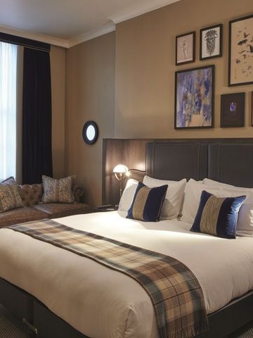 Geräumiges Zimmer mit Kingsize-Bett, Sofagarnitur und Kunstwerken