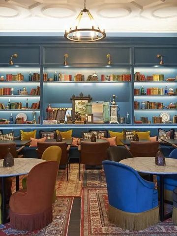 Gemütliche Lounge mit blauen Bücherregalen, Sesseln und bunten Kissen