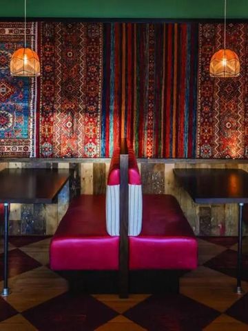 Restaurantbereich mit roten Sitzbänken, Holztischen und orientalischen Teppichen
