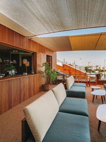 Terrassenlounge mit Sitzgelegenheiten und Bar unter Sonnenschutz im The Vintage Lisbon Hotel