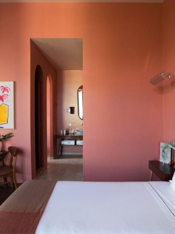 Elegantes Hotelzimmer mit warmen Rottönen und Kunst an der Wand