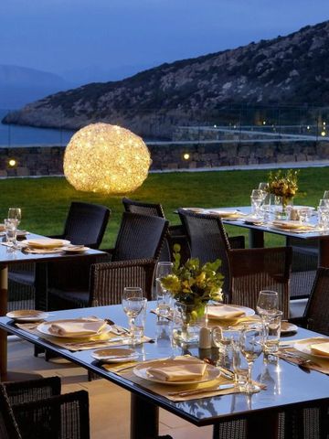 Elegante Terrasse mit gedeckten Tischen am Meer bei Sonnenuntergang