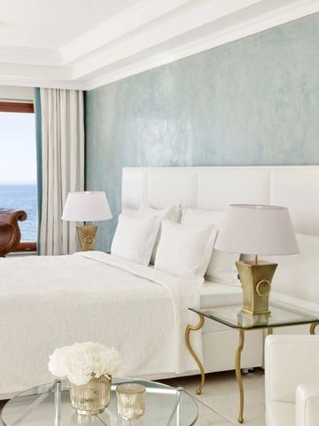Geräumiges Hotelzimmer mit großem Bett, Meerblick und luxuriösen Möbeln.