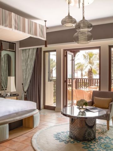 Helles Zimmer mit King-Size-Bett und Balkon mit Palmenblick.