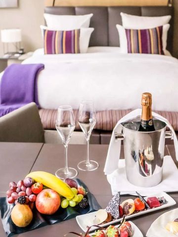 Luxuszimmer mit Doppelbett, Champagner und Früchtearrangement auf dem Tisch