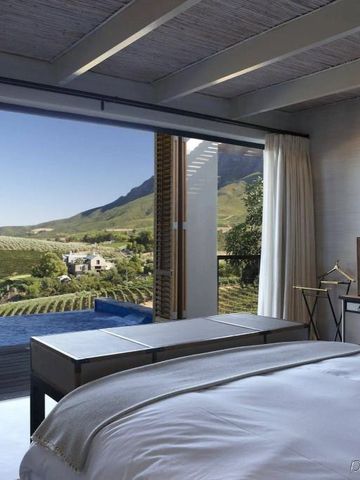 Helles Schlafzimmer mit Blick auf Weinberge durch große Fenster.