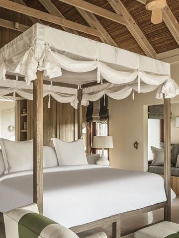 Luxuriöses Schlafzimmer mit Baldachinbett und Holzdach im tropischen Design.