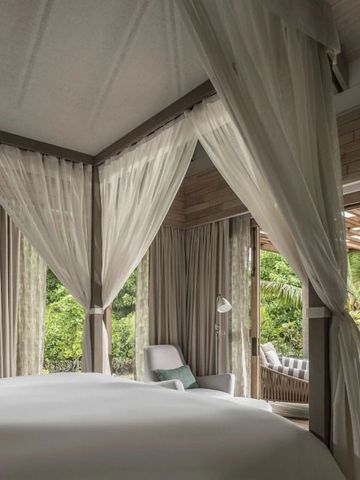Gemütliches Schlafzimmer mit Baldachinbett und Blick auf einen tropischen Garten.
