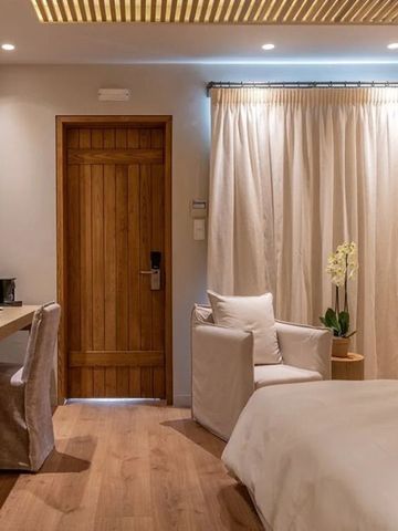 Einladendes Hotelzimmer mit Schreibtisch, Sessel und Holztür.