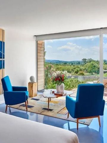Helles Zimmer mit blauen Sesseln und Terrasse mit Blick auf die Landschaft