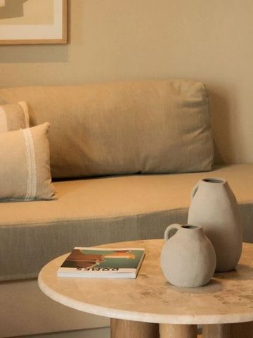 Elegante Sitzecke mit Keramikvasen und stilvollen Kissen auf dem Sofa.